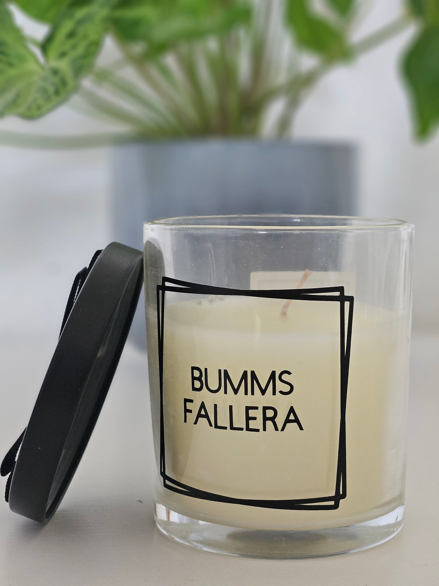 Eine Duftkerze mit Deckel und einem frechen Spruch auf dem Glas. Von vorne fotografiert.