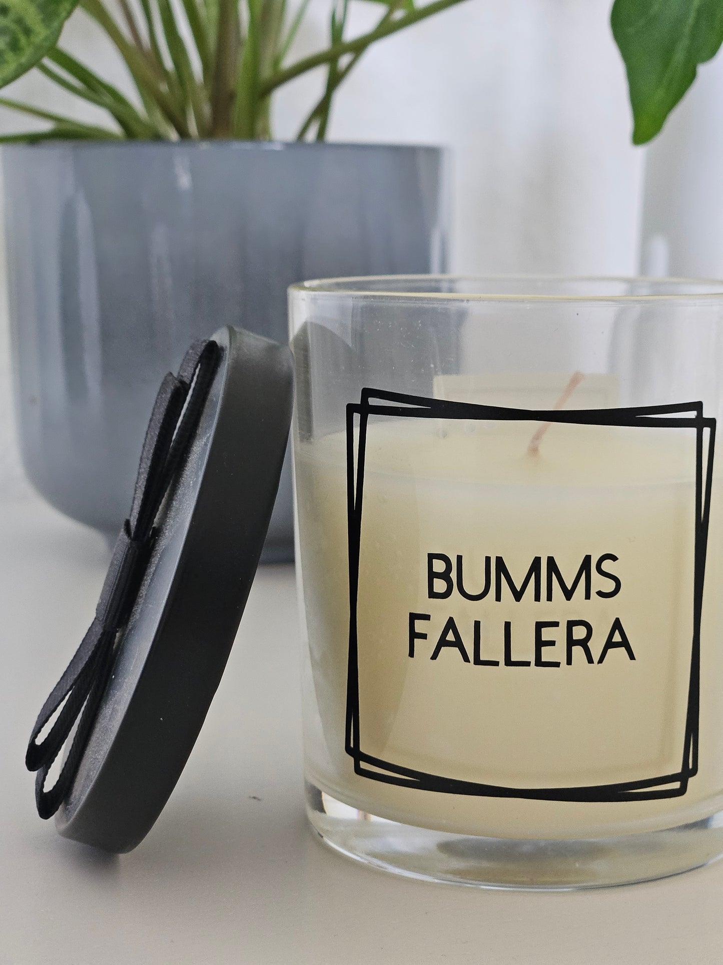 Eine Duftkerze mit Deckel und einem frechen Spruch auf dem Glas. Von links fotografiert.
