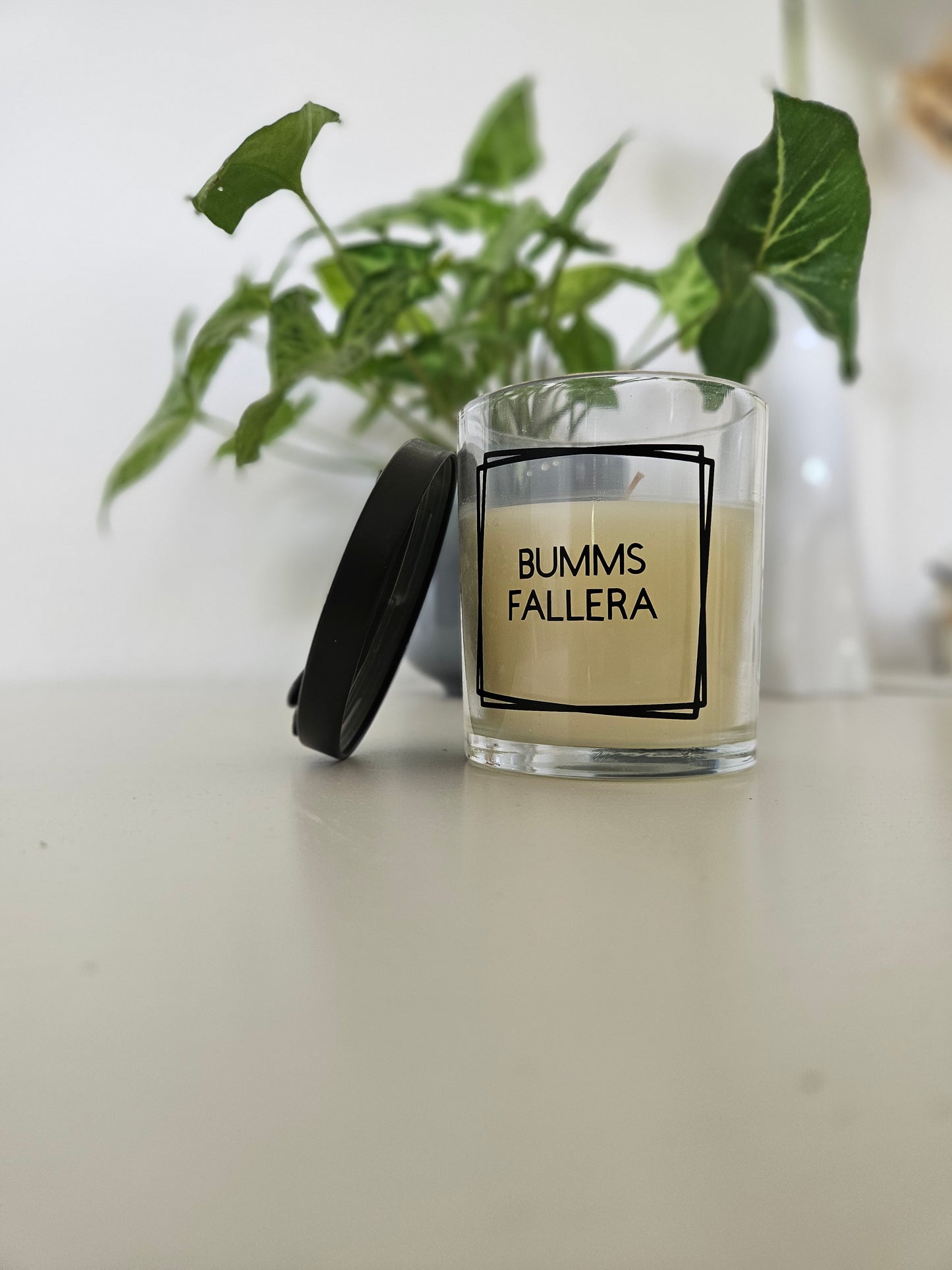 Eine Duftkerze mit Deckel und einem frechen Spruch auf dem Glas. Von unten fotografiert.