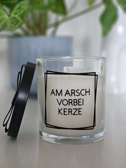 Eine Duftkerze mit Deckel und einem witzigen Spruch auf dem Glas, von vorne fotografiert