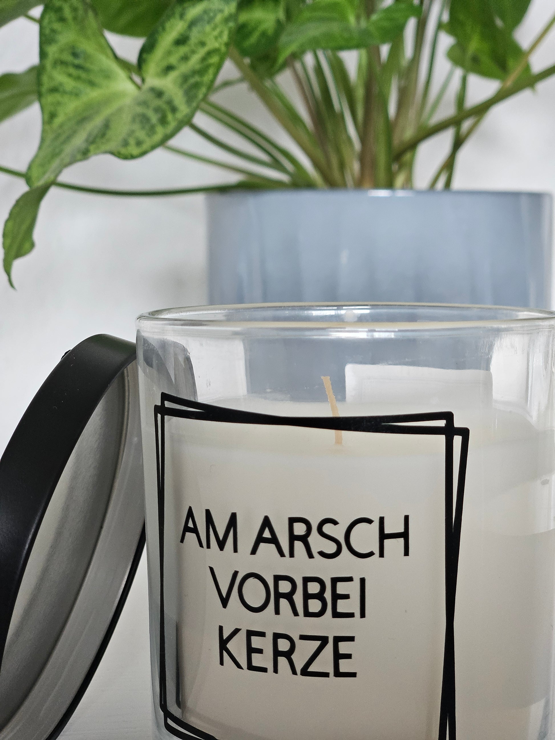 Eine Duftkerze mit Deckel und einem witzigen Spruch auf dem Glas, von oben fotografiert